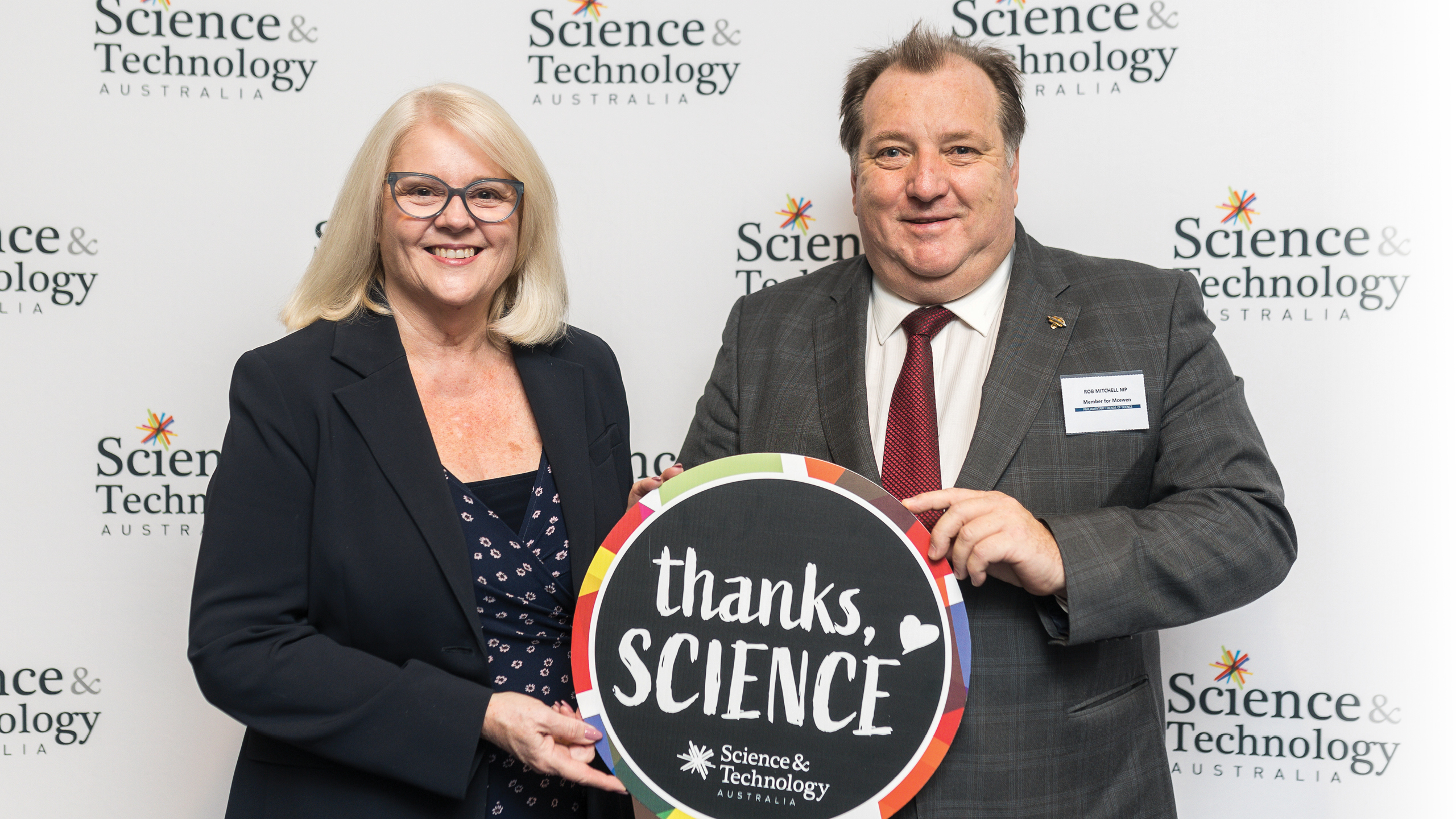 A photo of two smiling people, one woman and one man, holding a sign that reads "Thanks, Science"