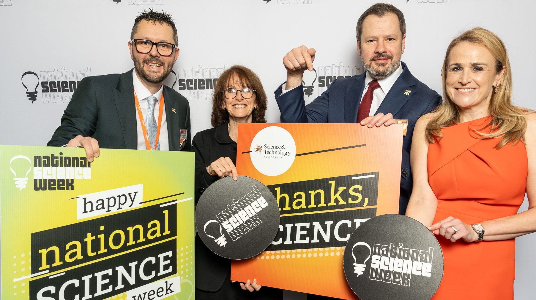 STA President Professor Mark Hutchinson, Dr Cathy Foley, Ed Husic MP and STA CEO Misha Schubert holding National Science Week signs and smiling at the camera.