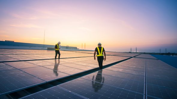 National Industry Growth Program - two engineers inspecting solar panels at sunset.