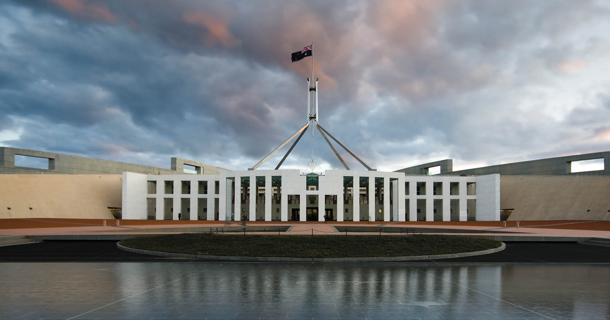 Parliament House Canberra with grey-blue-pink clouds in the background.