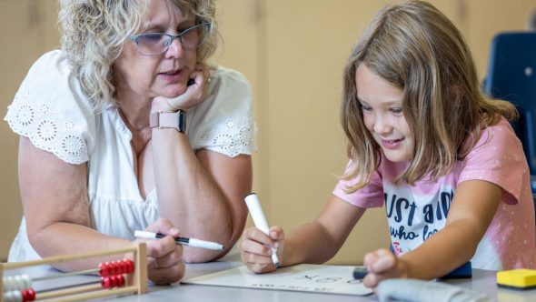 Teacher with student sitting at desk.