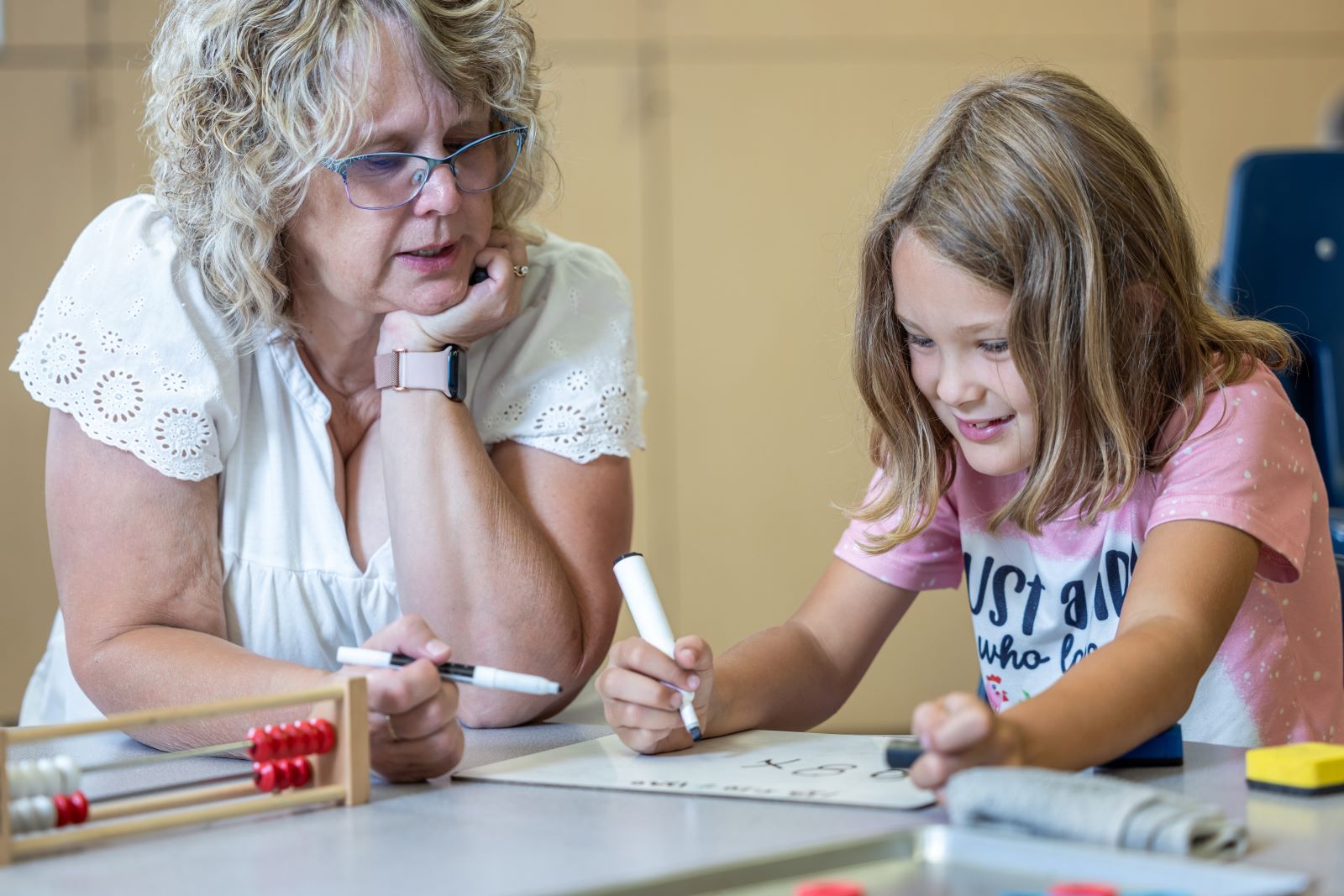 Teacher with student sitting at desk.